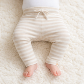 Baby trägt die gestreifte Little Dutch Babyhose Stripe Sand/White